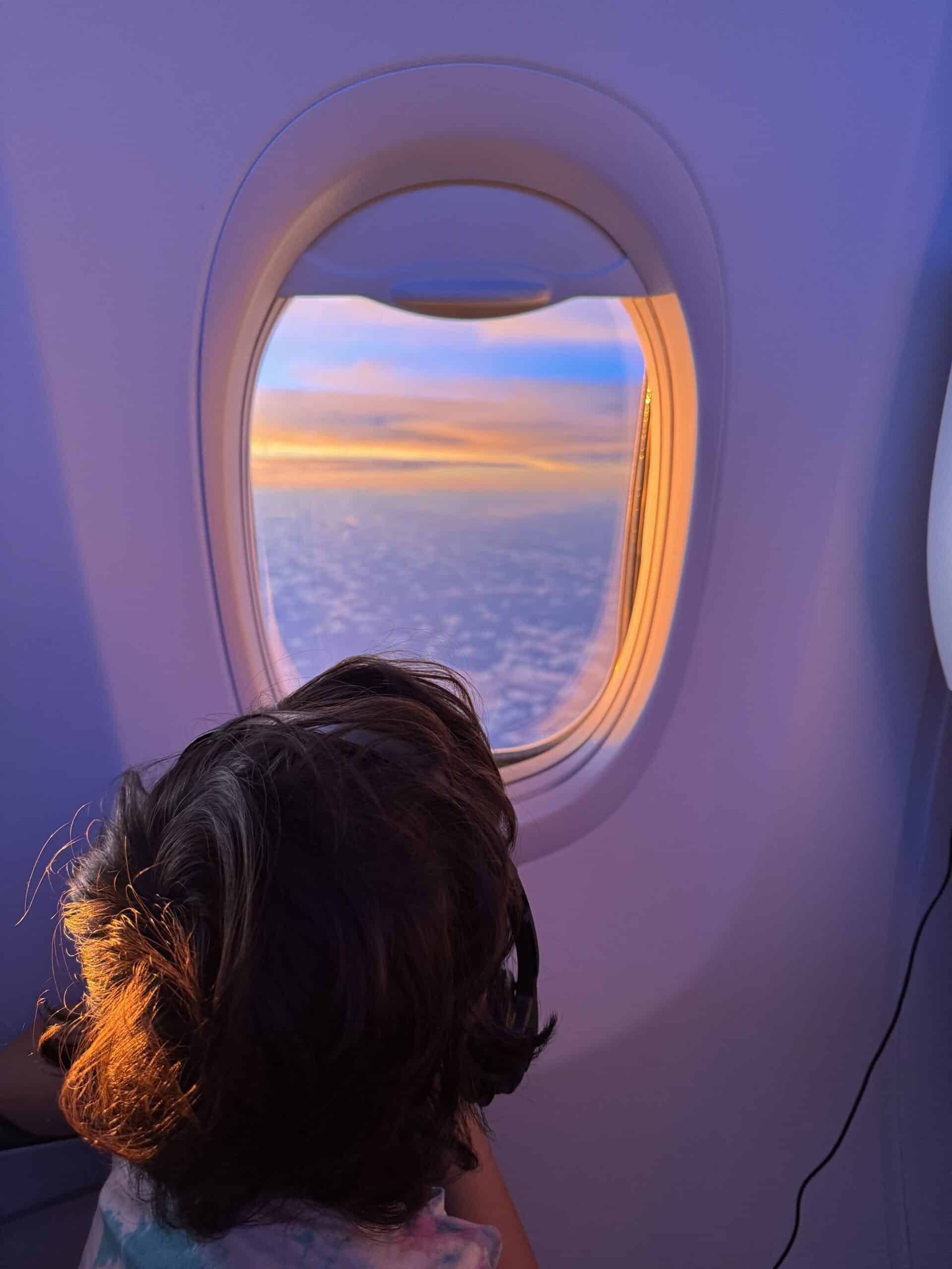 Young child looking out airplane window.